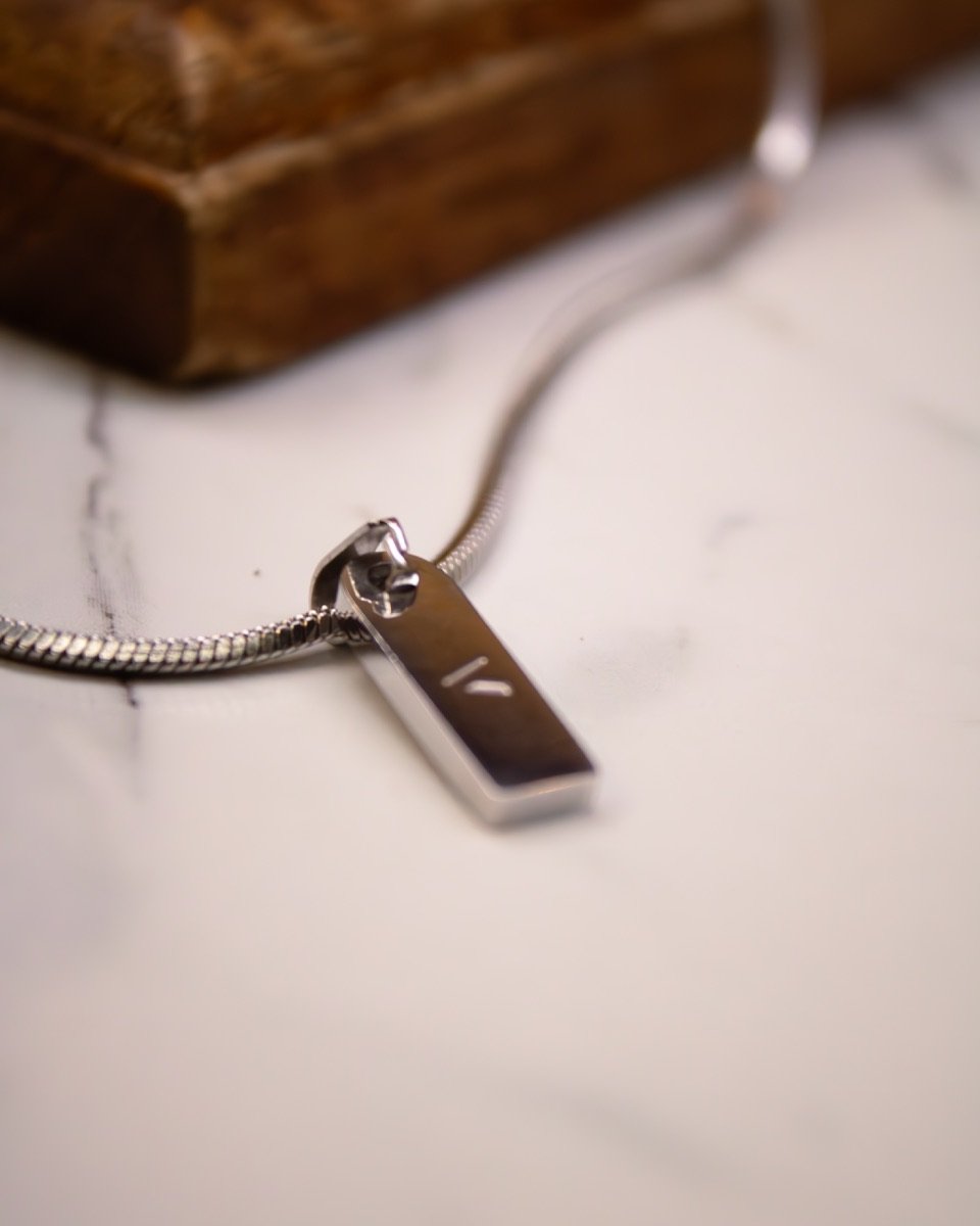 Cadena con dije Valha sobre mármol junto a una caja